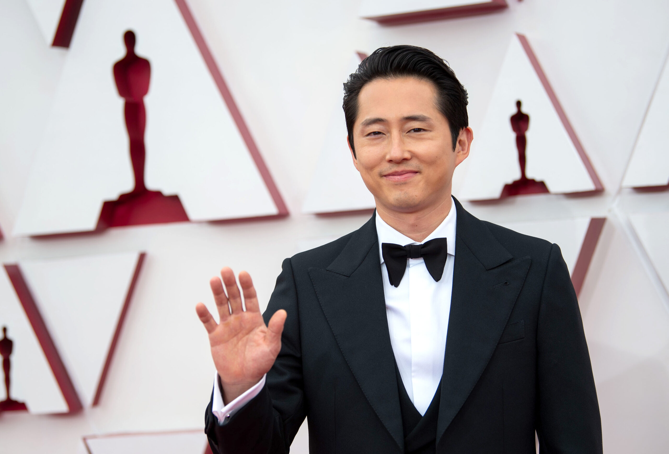 Steven Yeun in a tuxedo waving