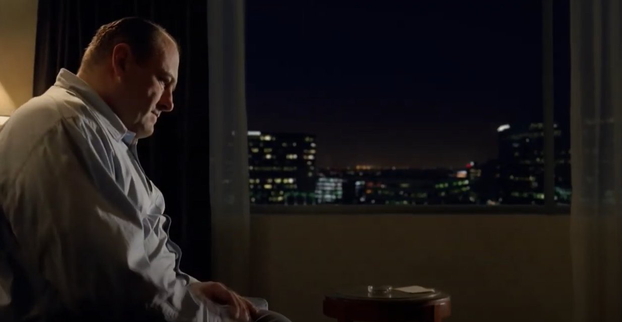 A character from The Sopranos sits in a hotel room, looking sad and alone.