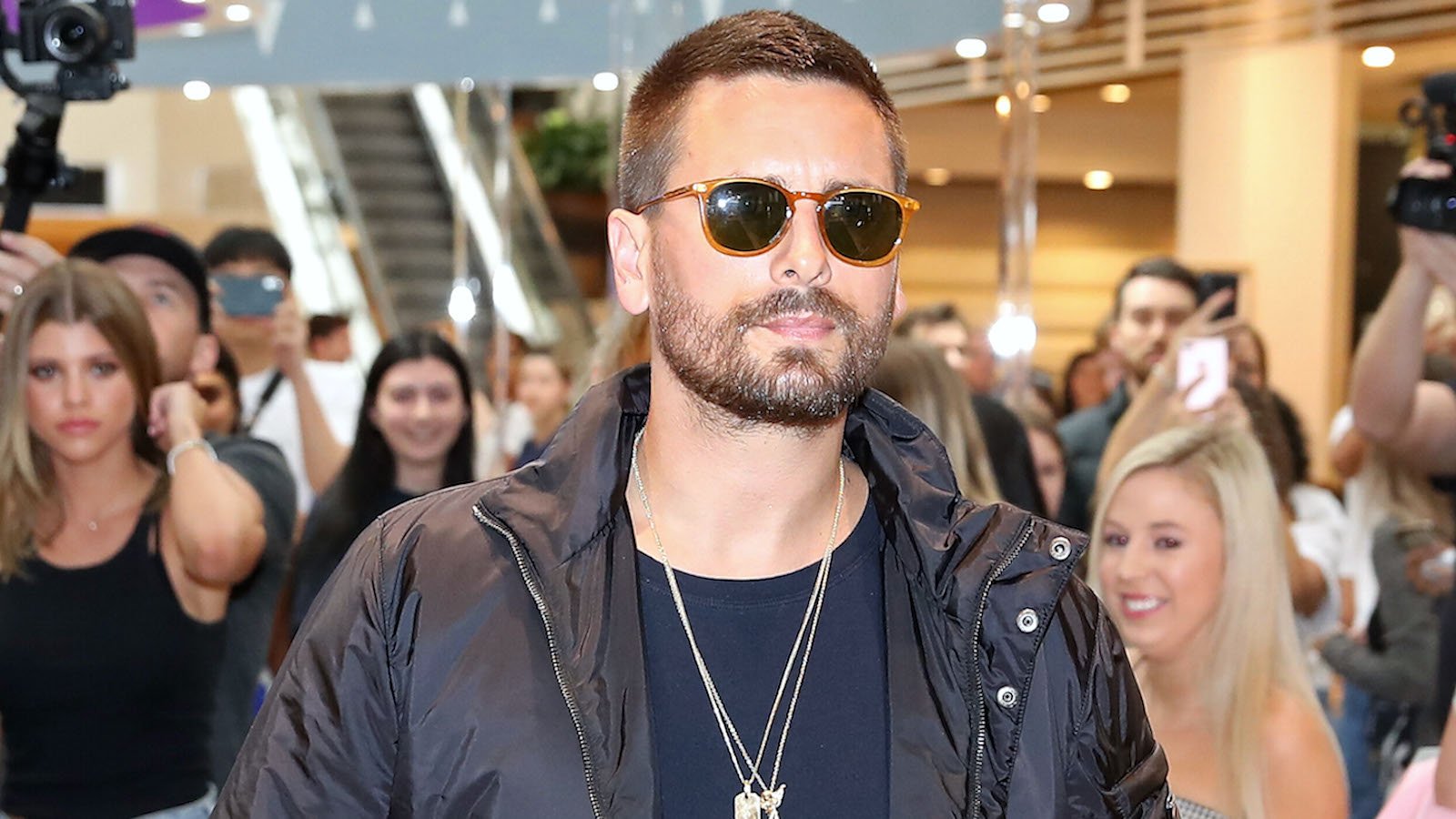 Scott Disick wearing sunglasses amongst a crowd of people