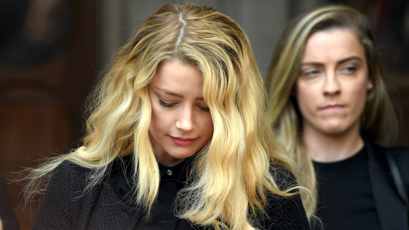 Amber Heard, head bowed with her sister Whitney Heard in the background