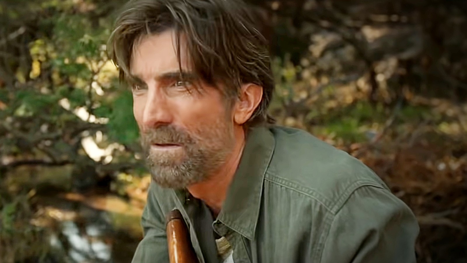 A shoulders-up portrait of Copley, outdoors, in a green shirt, looking off-camera