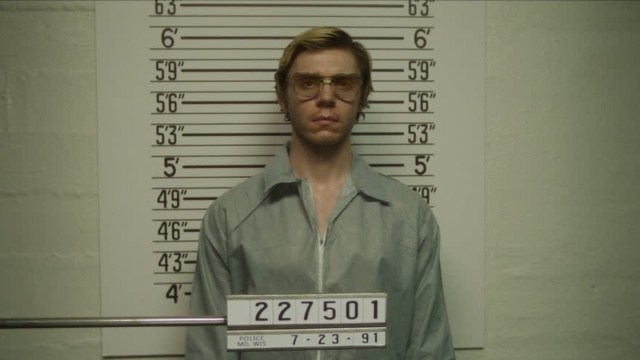 Evan Peters posing for a mugshot as Jeffrey Dahmer