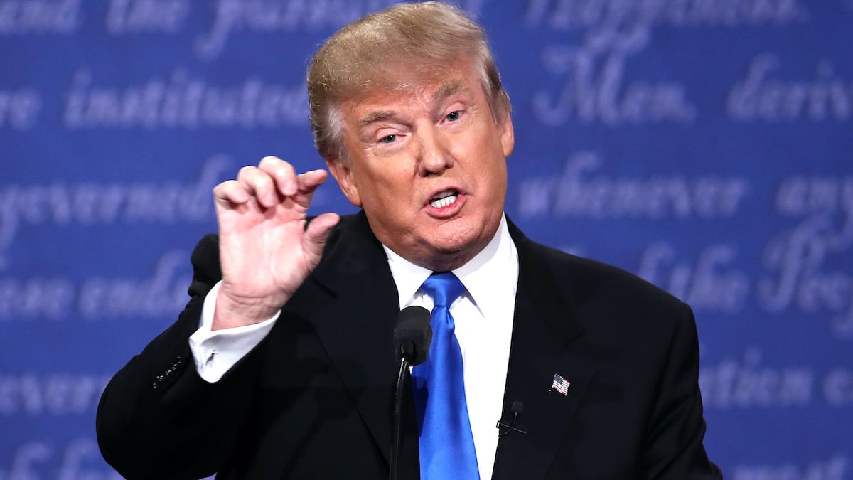 Donald Trump on stage in a black suit and blue tie