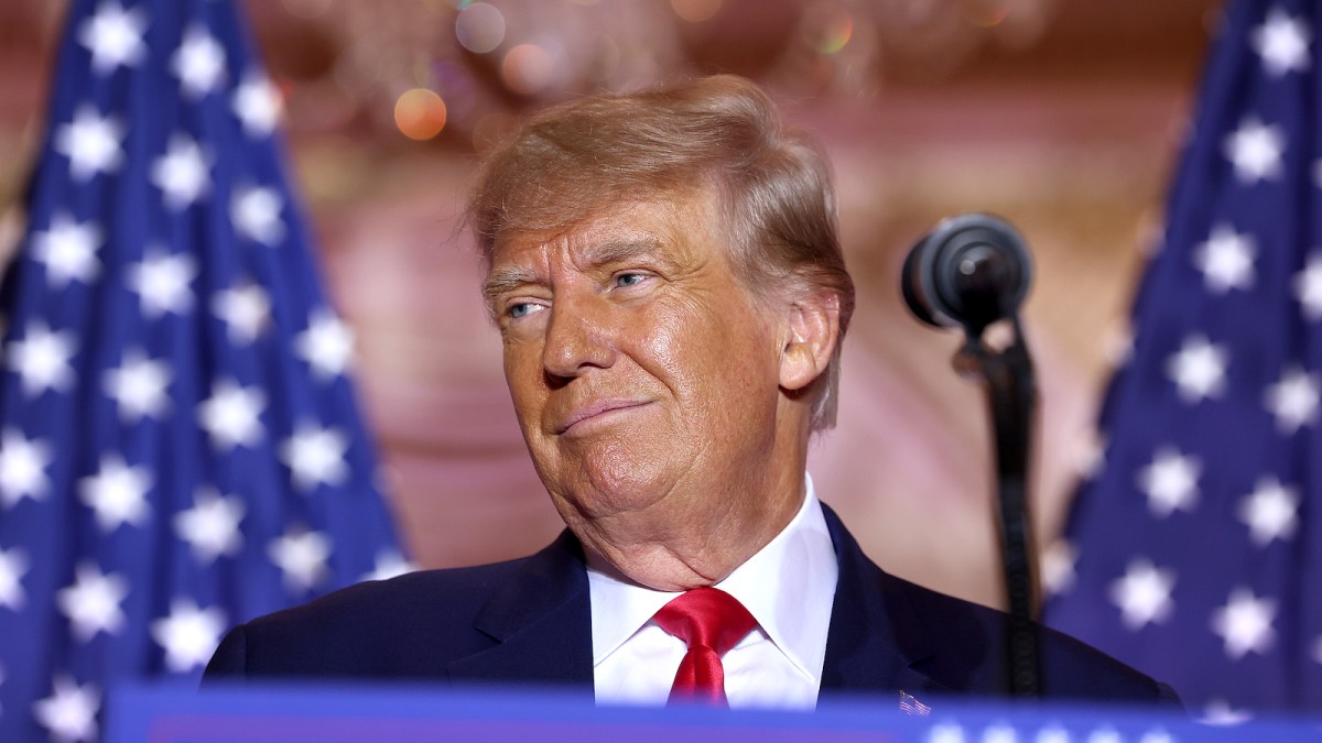 Donald Trump smiling at an audience while standing behind a podium.