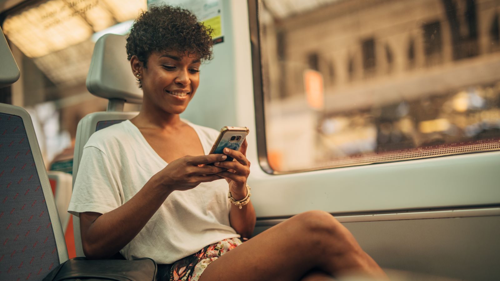 One woman, beautiful young lady riding in train, using mobile phone.