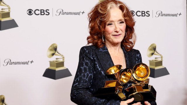 Bonnie Raitt holding three Grammy awards in her arms