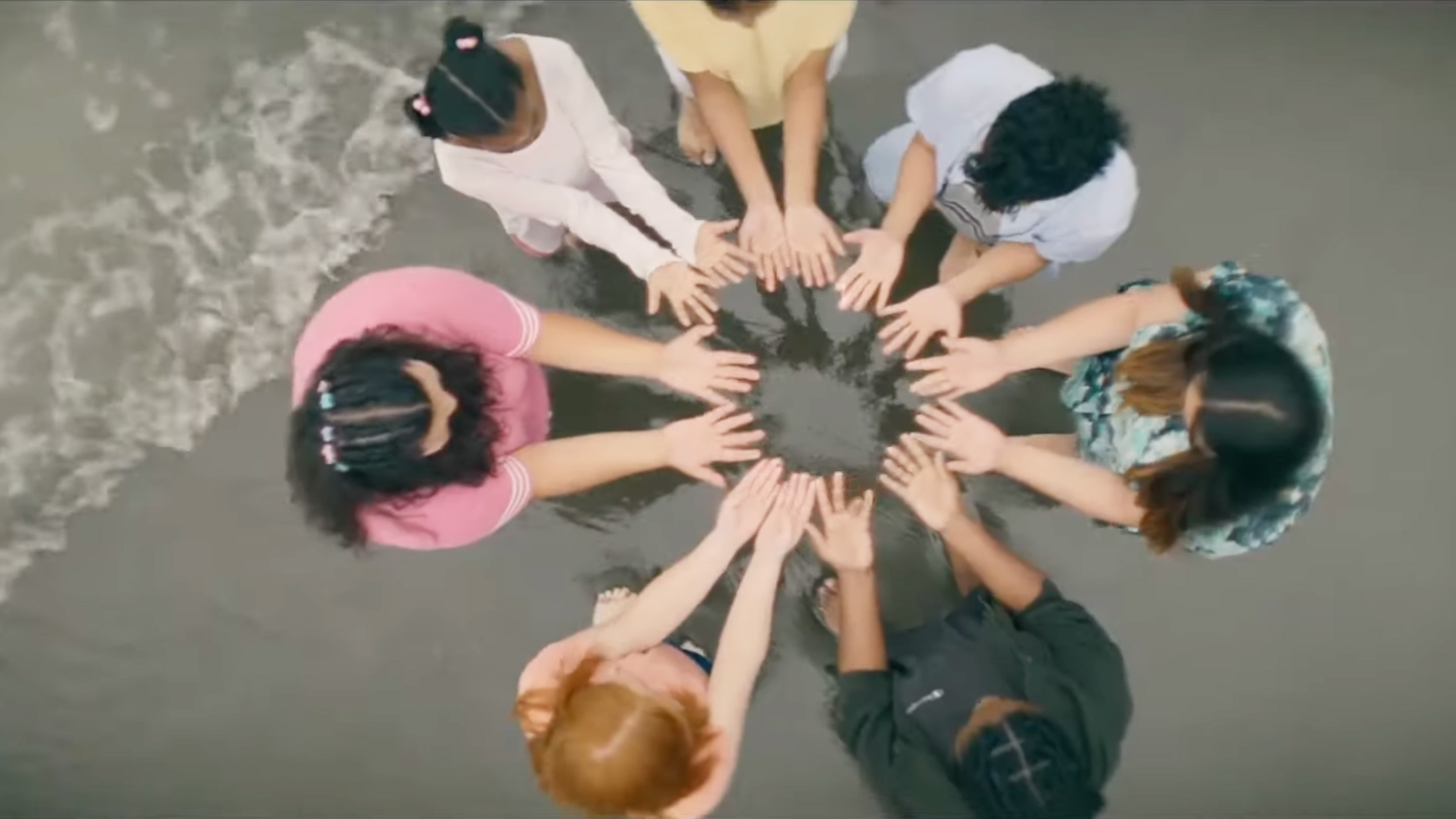 girls share electricity through their hands in a circle on the beach