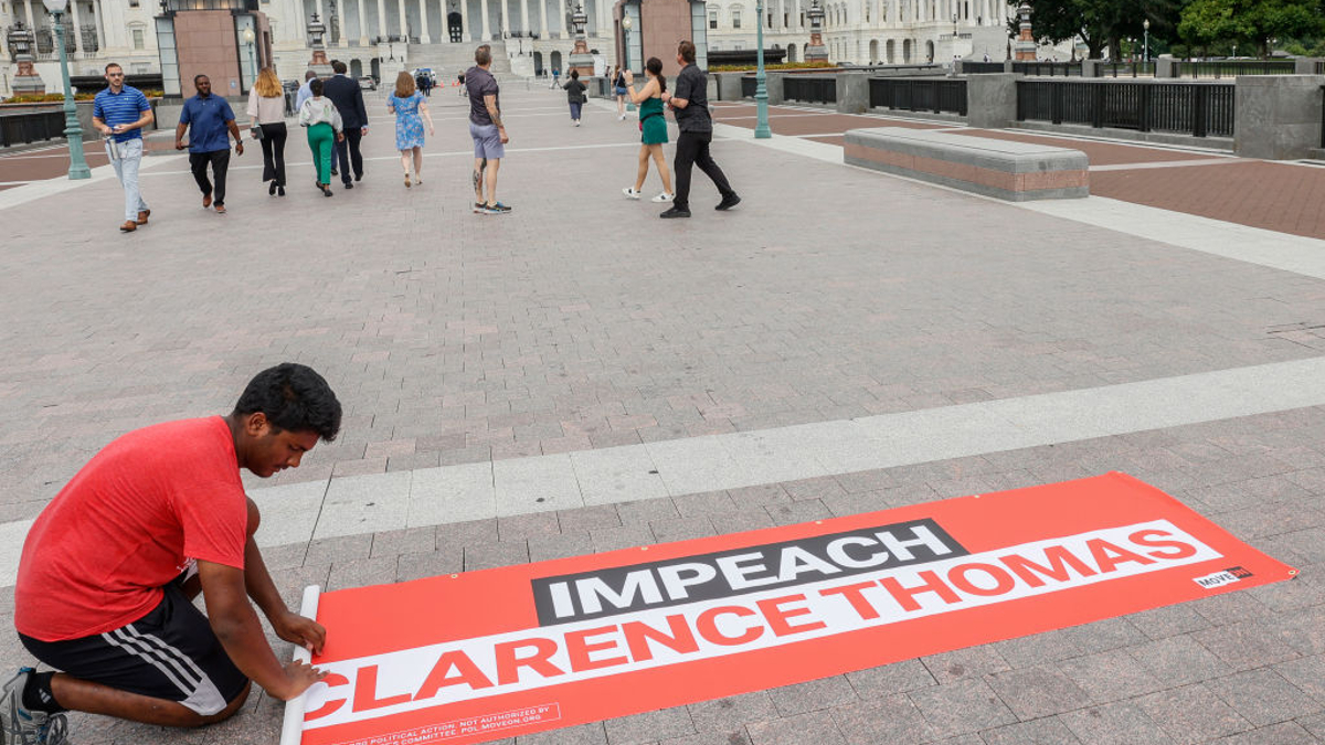 A MoveOn.Org volunteer rolls up an "Impeach Clarence Thomas" banner outside of the US Capitol after a demonstration where MoveOn.org delivered over 1 million signatures calling for Congress to immediately investigate and impeach Clarence Thomas at the US Supreme Court on July 28, 2022 in Washington, DC