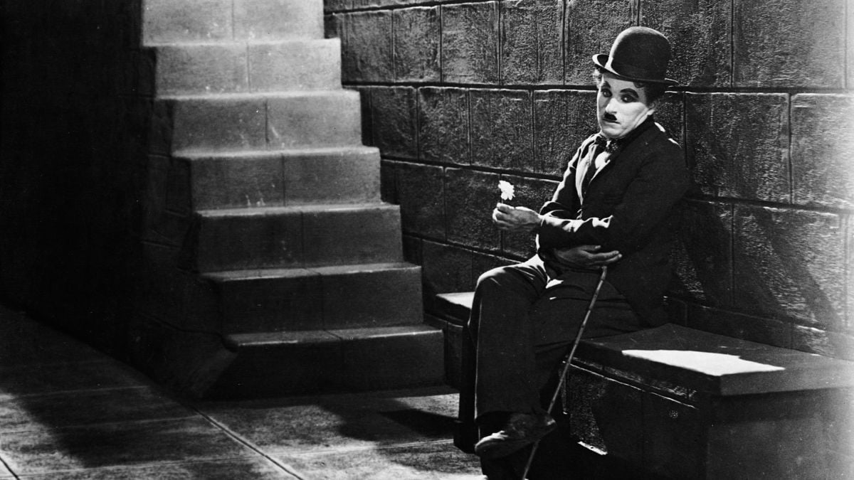 1931: Comic actor Charlie Chaplin (1889 - 1977) sitting forlornly at the bottom of the steps in a scene from the film 'City Lights'. 