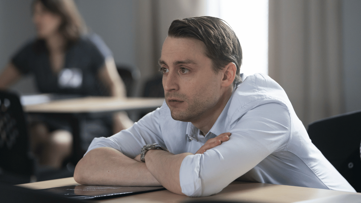 Roman (Kieran Culkin) leaning on a desk in 'Succession'