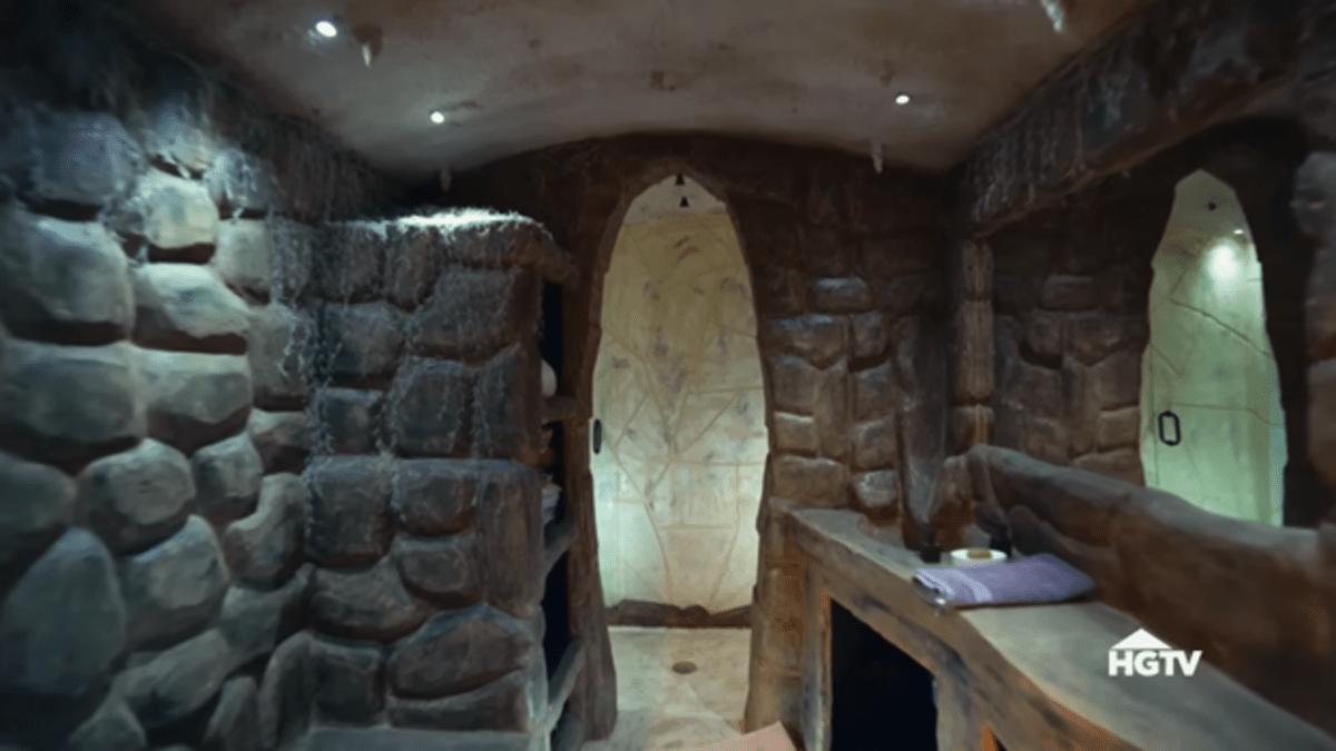 A stone cavern with a faux stone counter and linen closet leading to a four-person shower. 