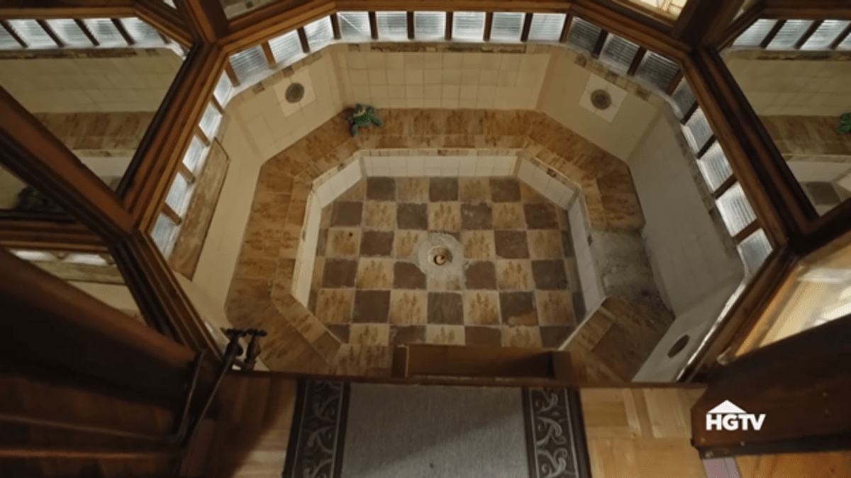 A hall that ends at a drop. Below is a very large octagonal tiled hot tub. 