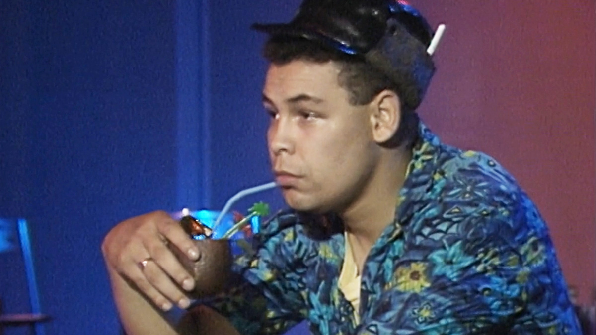 Lister has a far-away look in his eyes as he sadly sits in a tropical shirt clutching a cocktail in his hands in an empty nightclub. 