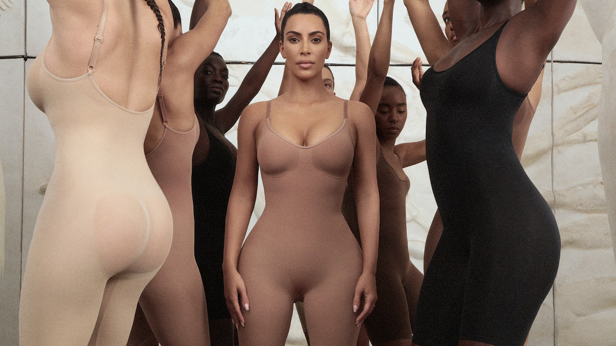 Kim Kardashian poses in shapewear with models surrounding her. 