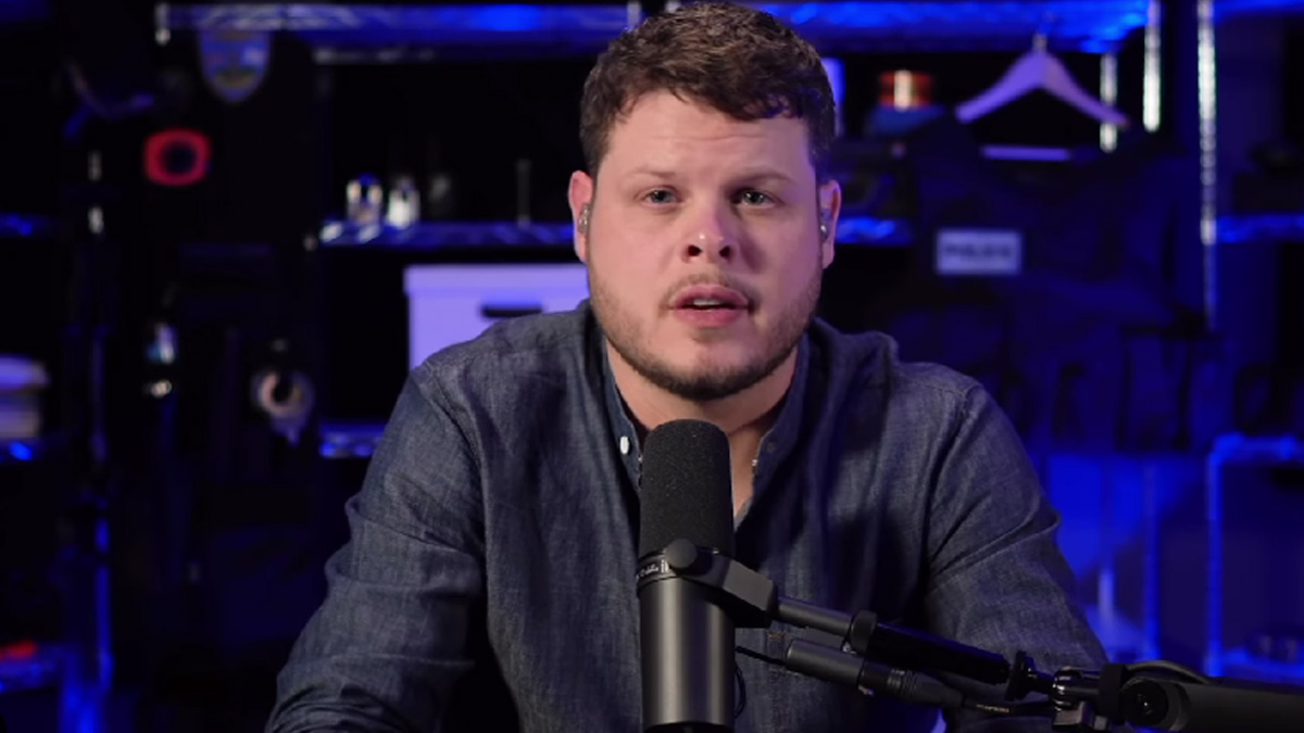 Derrick Levasseur wears a dark button-up shirt in a podcast recording room.